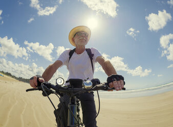 France, Bretagne, Sainte-Anne la Palud, Plage de Treguer, senior man riding mountain e-bike on beach - LAF01914