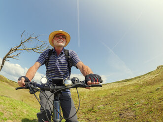 France, Bretagne, Sainte-Anne la Palud, Plage de Treguer, senior man riding mountain e-bike - LAF01915