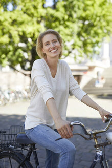 Porträt einer lachenden blonden Frau mit Fahrrad - PNEF00016
