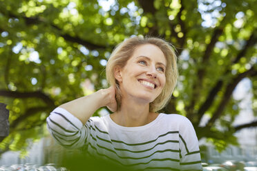 Portrait of happy blond woman in front of a tree - PNEF00021