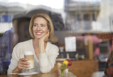 Porträt einer lächelnden Frau, die einen Latte Macchiato in einem Café trinkt - PNEF00023