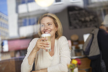 Porträt einer lächelnden Frau, die einen Latte Macchiato in einem Café trinkt - PNEF00024