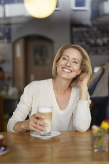 Porträt einer glücklichen Frau mit Latte Macchiato in einem Coffeeshop - PNEF00025