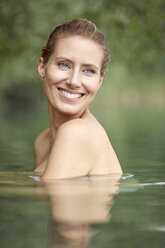 Porträt einer lachenden blonden Frau beim Baden im See - PNEF00048