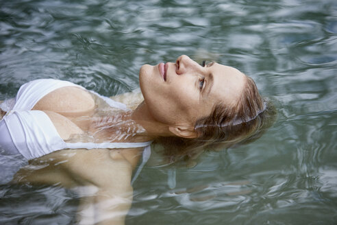 Porträt einer entspannten Frau, die auf dem Wasser schwimmt - PNEF00049