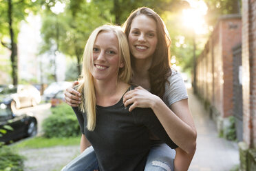 Young woman giving her friend a piggyback ride - PNEF00055