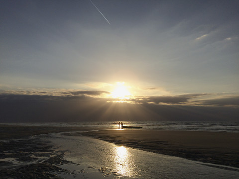 Belgien, Flanderns Küste, Sonnenuntergang, Menschen mit Boot am Nordseestrand, Ebbe, lizenzfreies Stockfoto