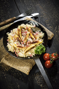 Bratpfanne mit fingerförmigen Kartoffelklößen mit Sauerkraut und Speck auf Jute - MAEF12451