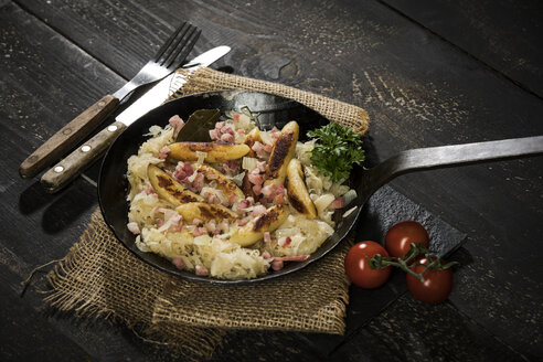 Bratpfanne mit fingerförmigen Kartoffelklößen mit Sauerkraut und Speck auf Jute - MAEF12452