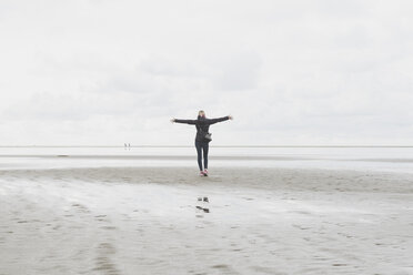 Niederlande, Ouddorp, Rückenansicht einer Frau mit ausgestreckten Armen, die im Herbst am Strand steht - CHPF00435