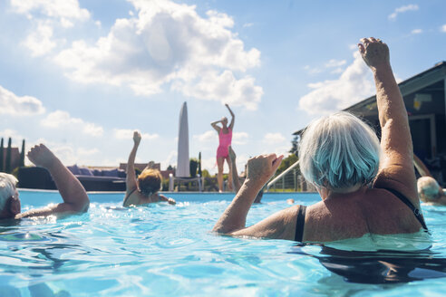 Group of seniors with trainer doing water gymnastics in pool - PNPF00104