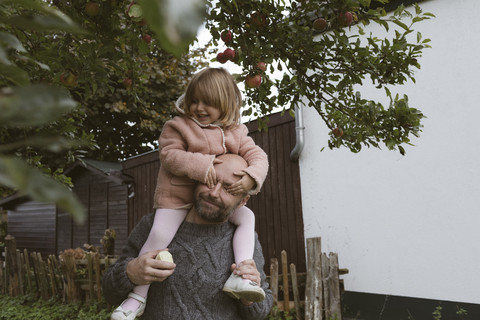 Father carrying his little daughter on shoulders stock photo