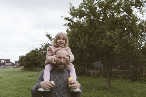 Father carrying his little daughter on shoulders stock photo