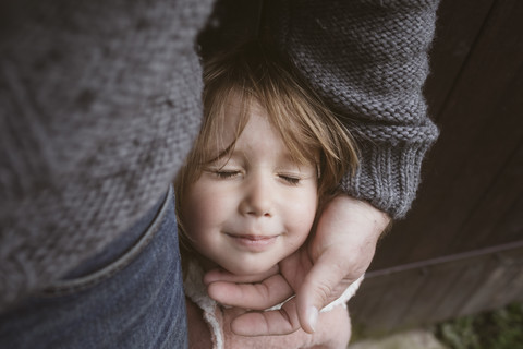 Porträt eines blonden kleinen Mädchens mit geschlossenen Augen, das neben seinem Vater steht, lizenzfreies Stockfoto