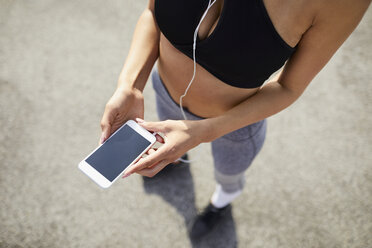 Nahaufnahme einer Frau, die ihr Smartphone während des Trainings hält - BSZF00054