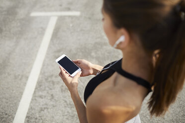 Nahaufnahme einer Frau, die ihr Smartphone während des Trainings hält - BSZF00055