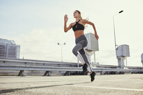 Young woman doing running exercises in the city - BSZF00057