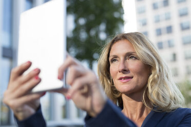 Businesswoman holding up tablet in the city - PNEF00092