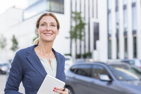 Lächelnde Geschäftsfrau mit Tablet in der Stadt, lizenzfreies Stockfoto