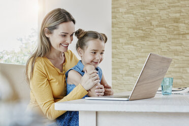 Glückliche Mutter mit Tochter zu Hause vor einem Laptop - RORF01011