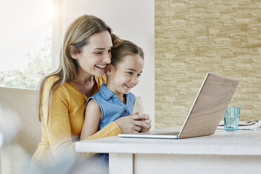 Glückliche Mutter mit Tochter zu Hause vor einem Laptop - RORF01014