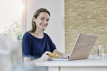 Porträt einer lächelnden Frau beim Online-Shopping zu Hause - RORF01015