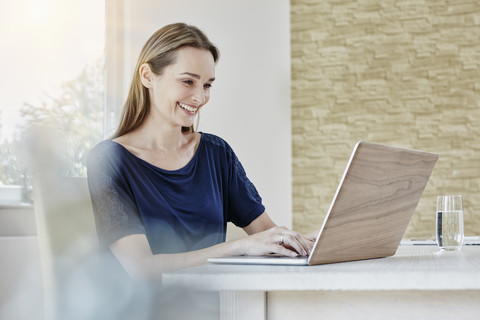 Glückliche Frau zu Hause am Laptop, lizenzfreies Stockfoto