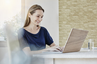 Happy woman at home using laptop - RORF01019