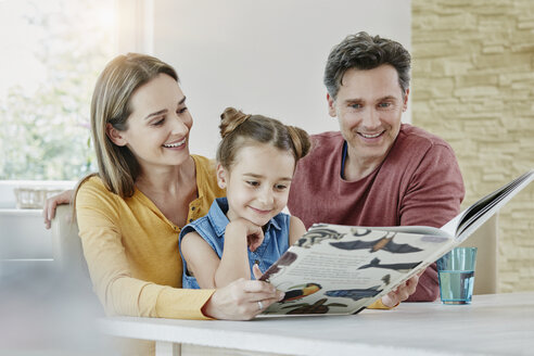 Glückliche Familie zu Hause beim Betrachten eines Bilderbuchs - RORF01022