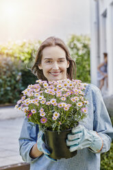 Porträt einer lächelnden Frau mit Blumentopf im Garten - RORF01023