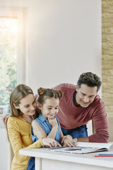 Glückliche Familie zu Hause beim Betrachten eines Bilderbuchs - RORF01025