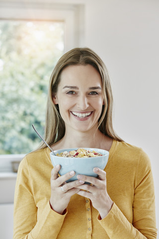 Portrait of happy woman holding bowl with muesli stock photo