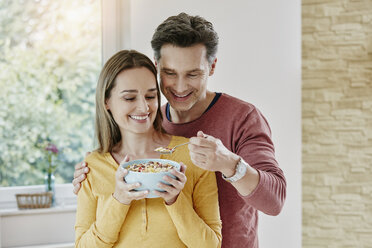 Happy couple sharing muesli at home - RORF01039