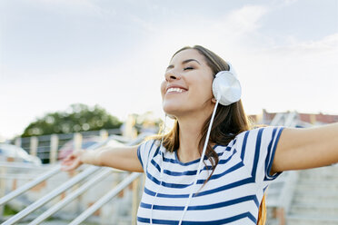 Glückliche junge Frau mit Kopfhörern, die den Sommer genießt - BSZF00072