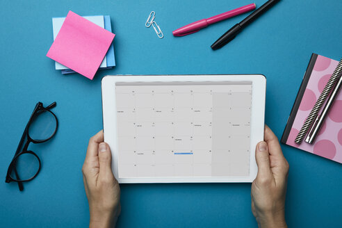 Top view of woman holding tablet with calendar on desk - RBF06085