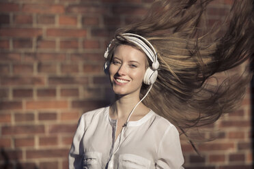 Portrait of happy woman with headphones and blowing hair - PNEF00123