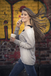 Porträt einer lachenden Frau mit Kaffee zum Mitnehmen am Telefon - PNEF00130