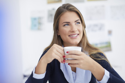 Smiling young woman having coffee break in office stock photo