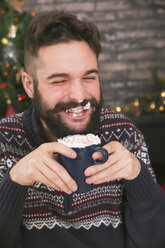 Porträt eines lachenden Mannes, der heiße Schokolade mit Schlagsahne und gehackten Zuckerstangen trinkt - RTBF01042