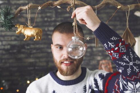 Porträt eines Mannes, der durch eine transparente Weihnachtskugel blickt - RTBF01044