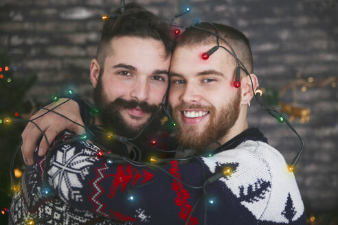 Portrait of happy gay couple with chain of lights at Christmas time - RTBF01048