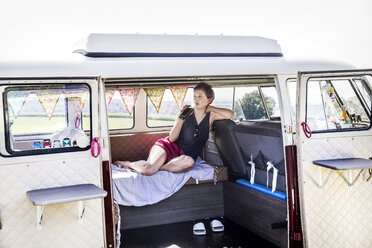 Woman relaxing in a van drinking from bottle - FMKF04531