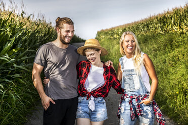 Glückliche Freunde auf dem Feldweg an einem Maisfeld - FMKF04572