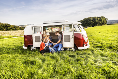 Friends having picnic in a van parked on field in rural landscape stock photo