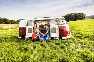 Freunde machen ein Picknick in einem auf einem Feld geparkten Lieferwagen in einer ländlichen Landschaft - FMKF04580