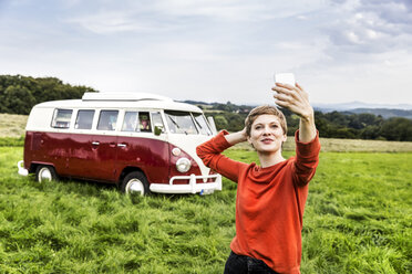 Frau, die ein Selfie vor einem Lieferwagen in einer ländlichen Landschaft macht - FMKF04589