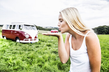 Frau küsst Van-Modell neben Van in ländlicher Landschaft - FMKF04592