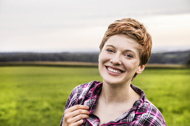 Portrait of smiling woman in pyjama in rural landscape - FMKF04594
