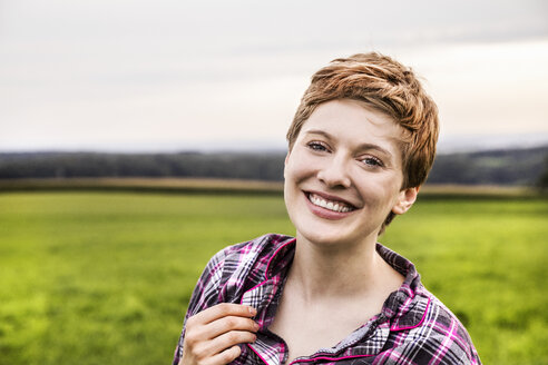 Porträt einer lächelnden Frau im Pyjama in einer ländlichen Landschaft - FMKF04594