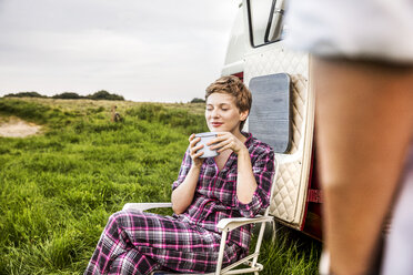 Woman in pyjama enjoying coffee at a van in rural landscape - FMKF04595